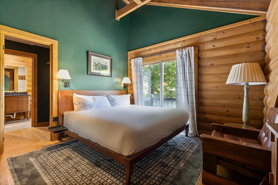 King bedroom with a green wall and curtains drawn back from the deck door
