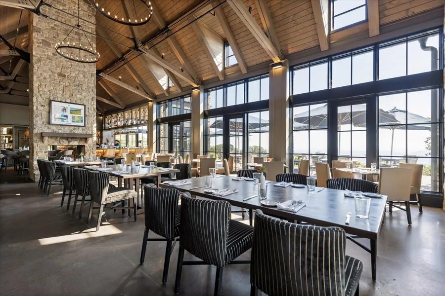 Dining room with vaulted timber ceiling, stone chimney and a wall of windows over the valley