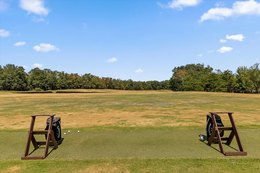 Practice range with turf hitting stations and mown grass running to the tree line
