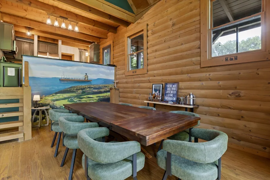 Walnut dining table with green upholstered chairs beneath the Keep mural