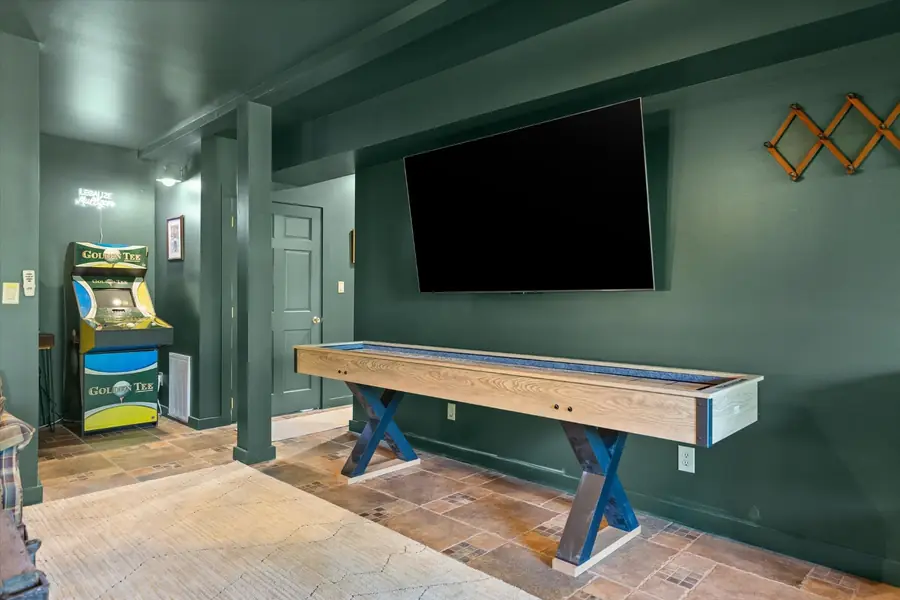 Full length shuffleboard table in a green paneled room